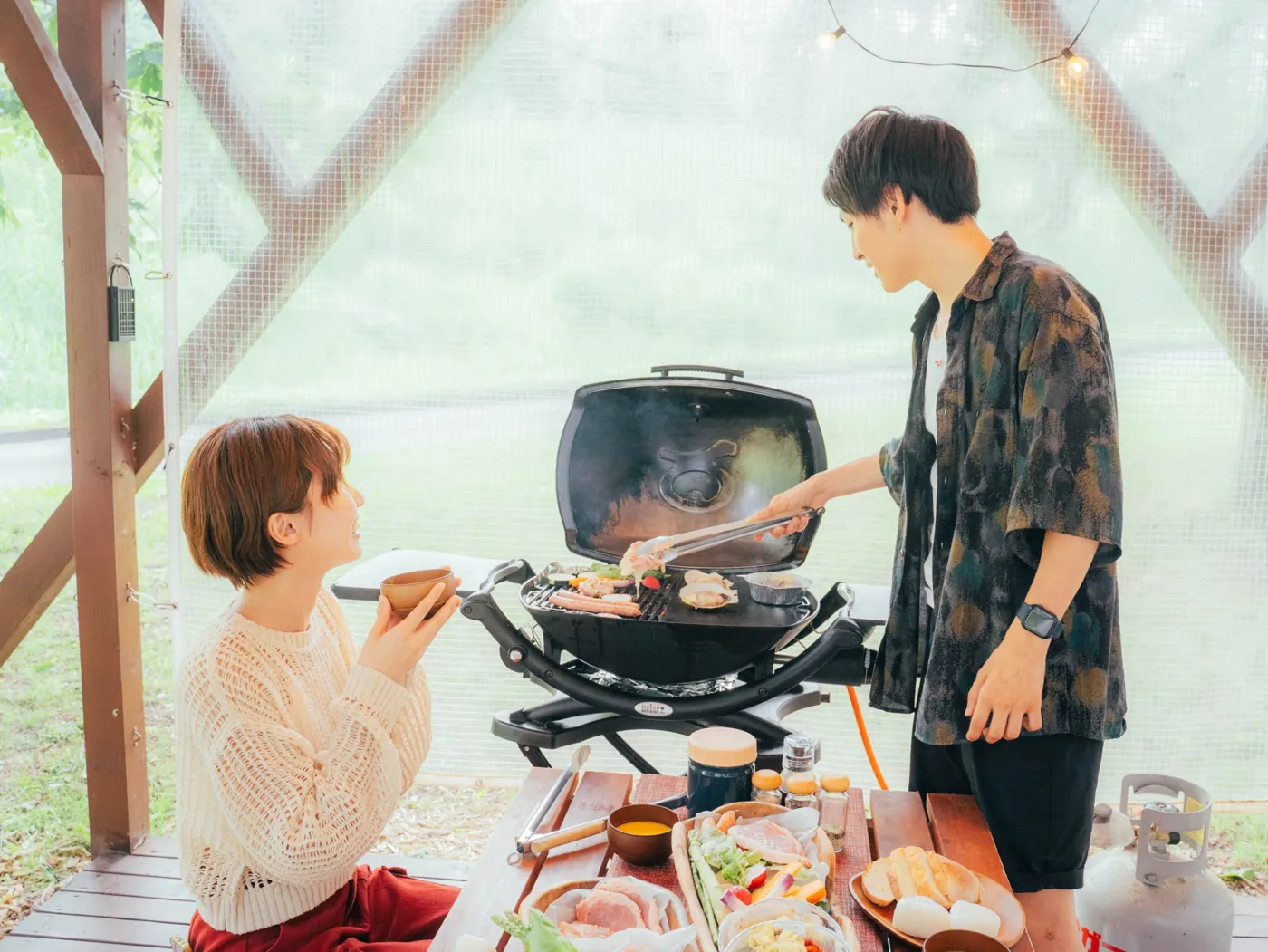 屋根付きテラスでBBQを楽しむ2人の写真
